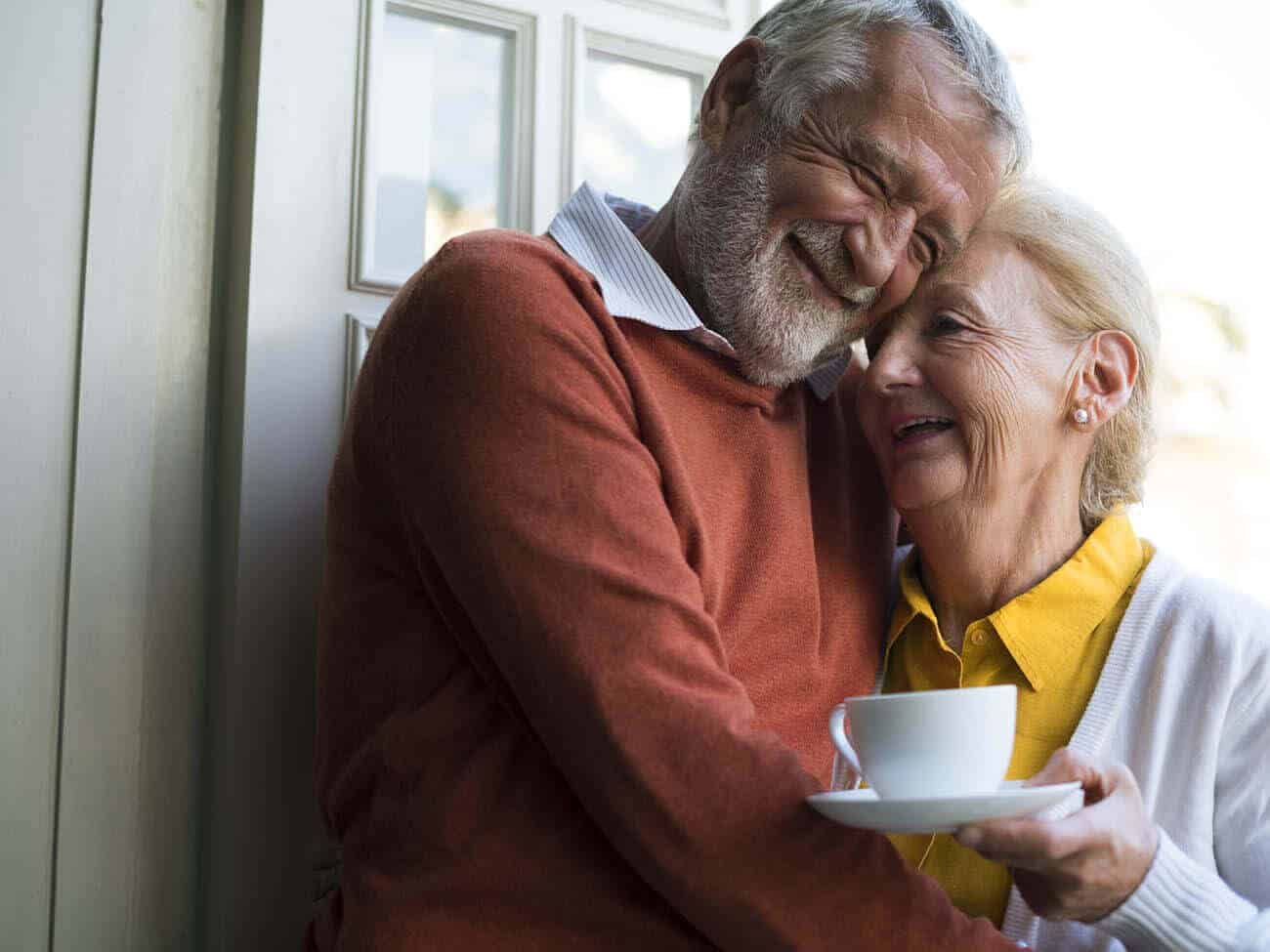 senior couple hugging and holding a cup of coffee