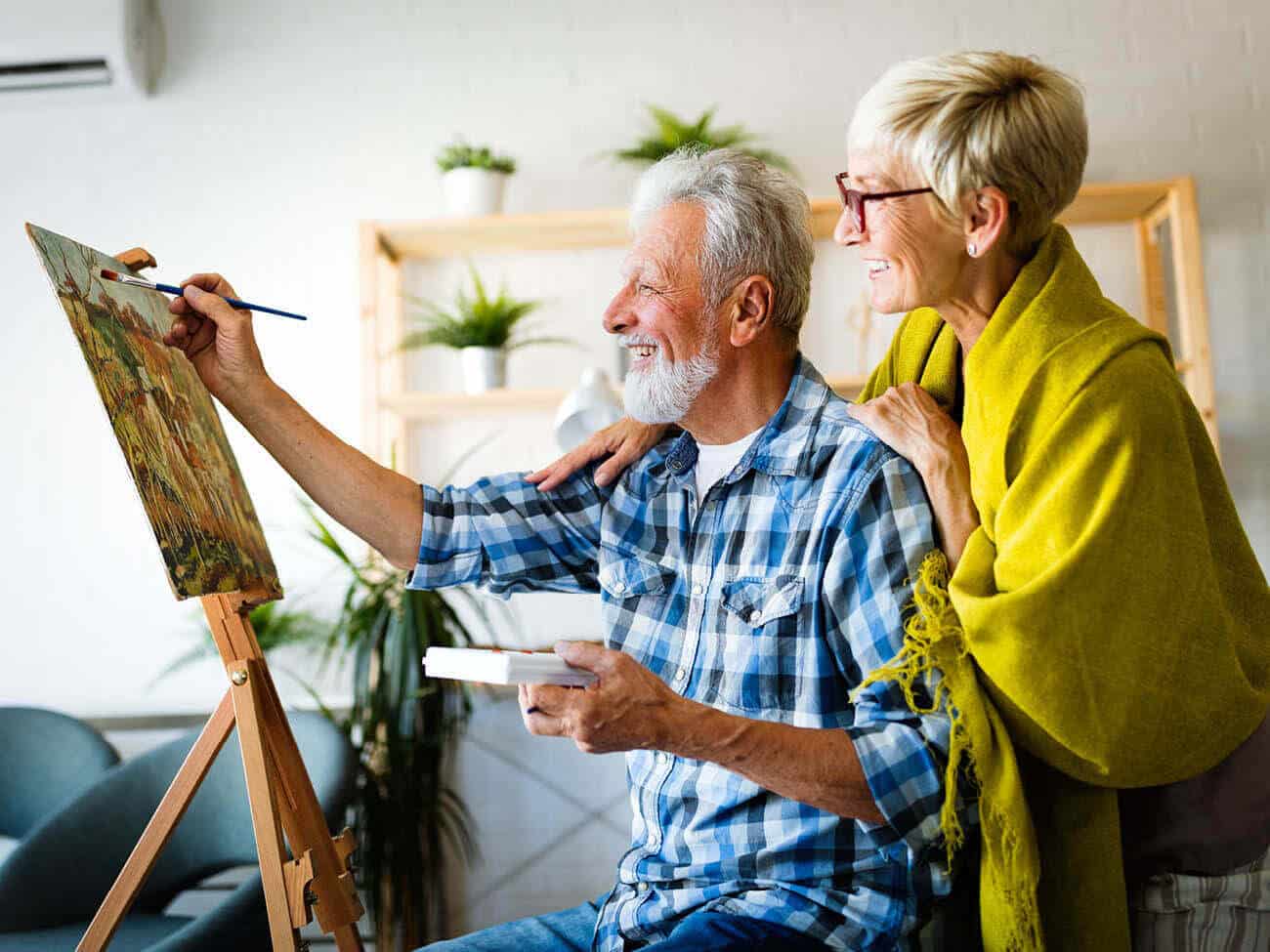 senior man paints while senior woman watches