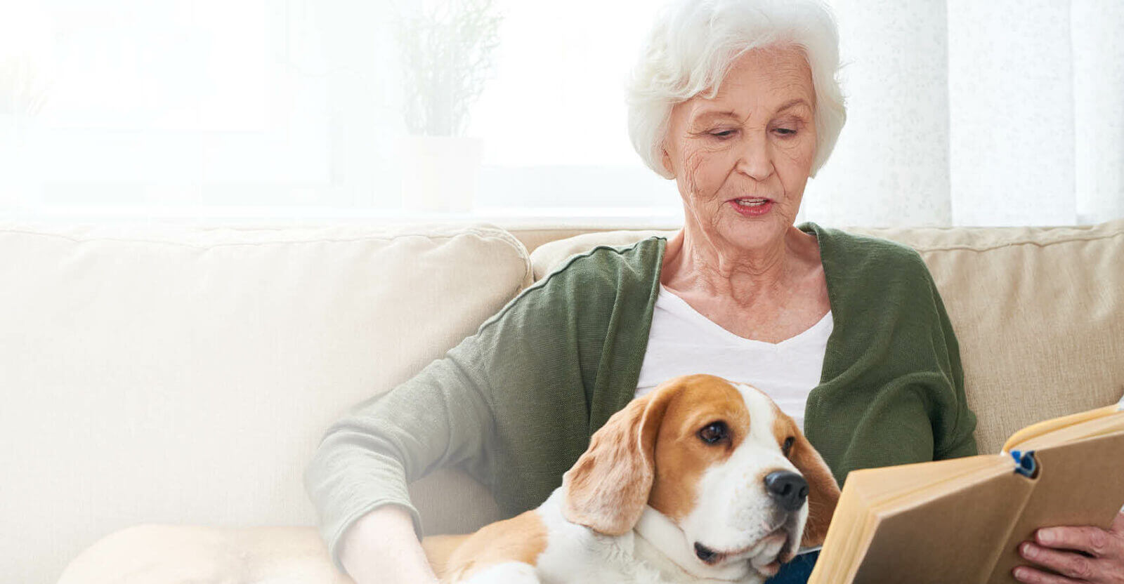 senior woman reading a book and petting her dog