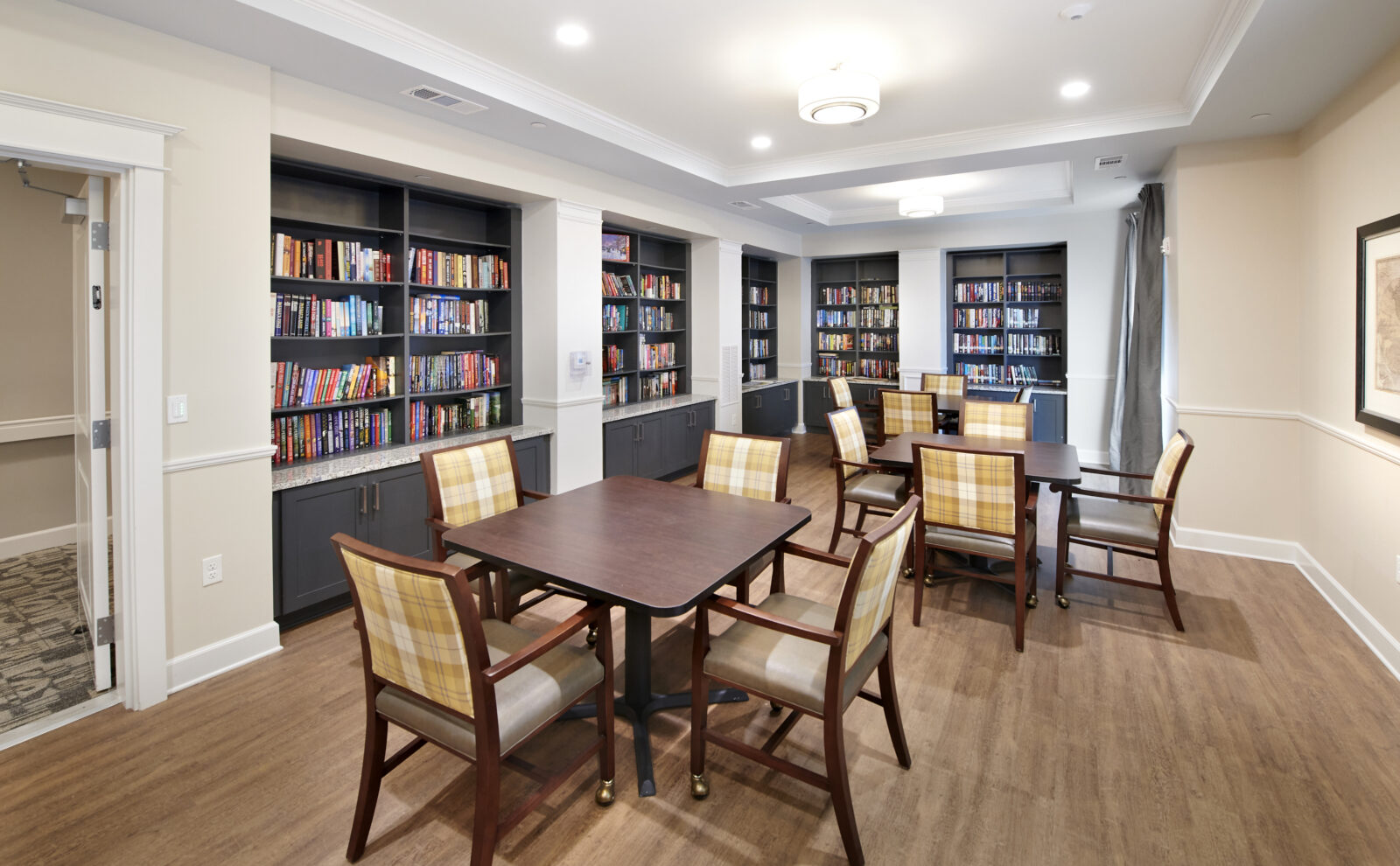 stripped chairs at square tables with books on gray shelves