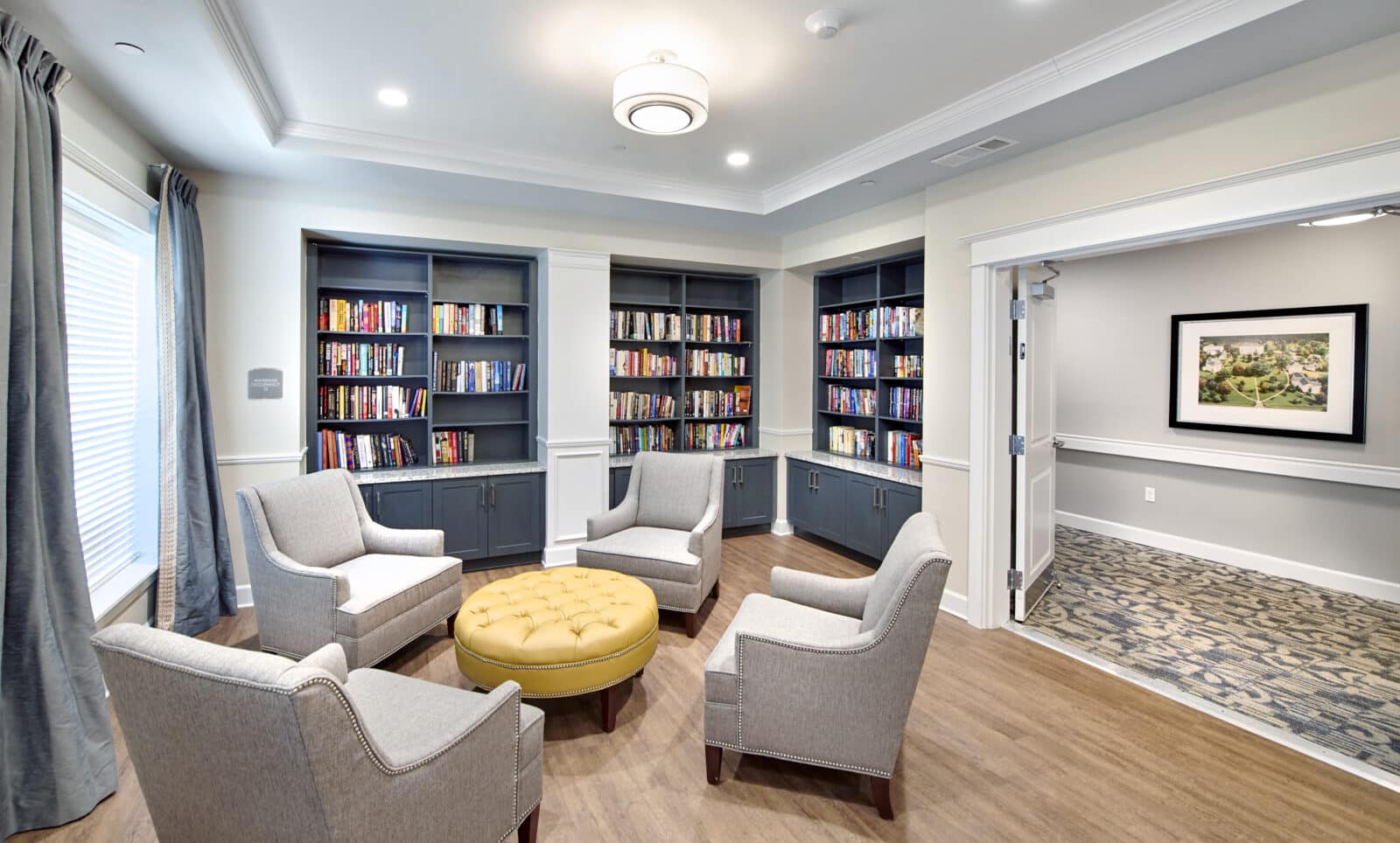 library with built in bookcase filled with books, four chairs and ottoman