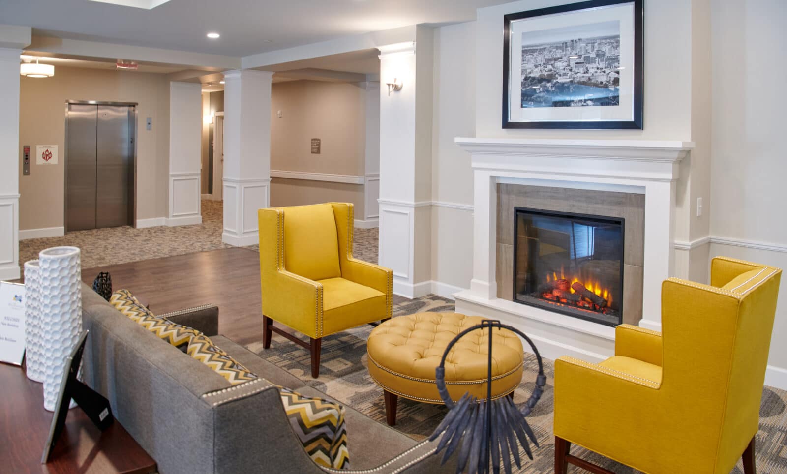 fireplace with yellow chairs, round ottoman and couch with chevron pillows