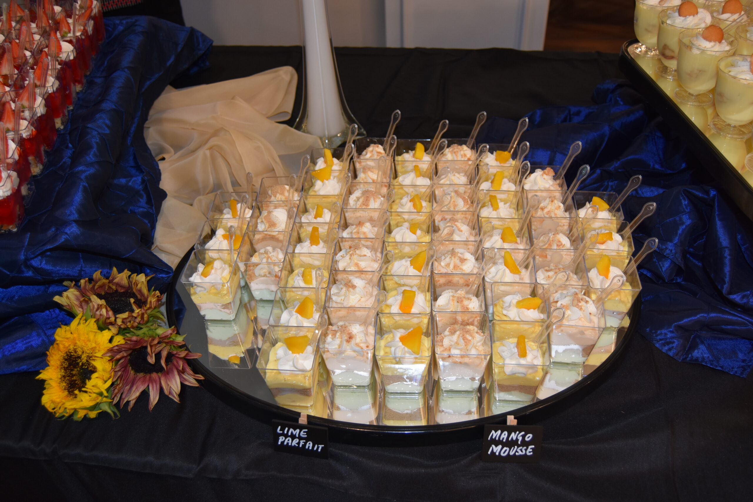 yellow and white dessert cups displayed on a round mirror with spoons