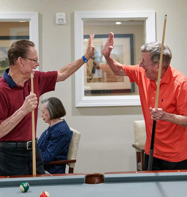 two men playing billiards and high fiving